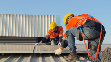Electrical engineers examining the solar panels installation on the roof of factory.