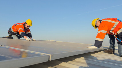 Electrical engineers examining the solar panels installation on the roof of factory.