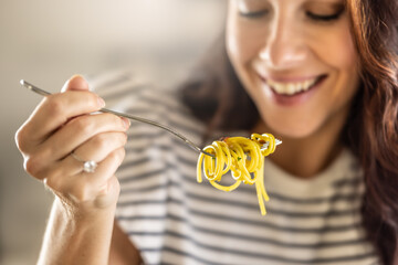 Young woman enjoys eating spaghetti. He has Aglio e Olio pasta twisted on his fork