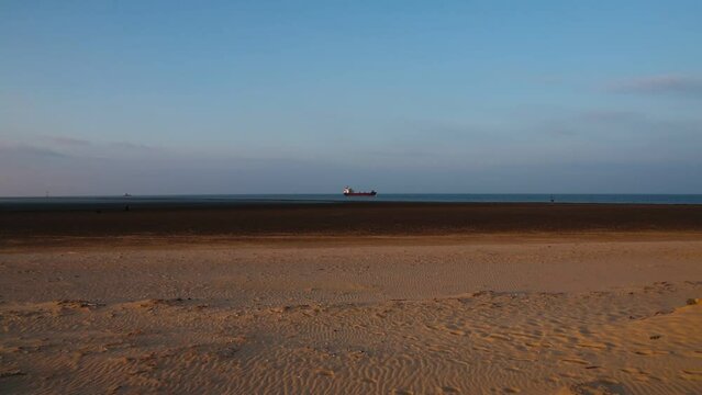 Evening atmosphere on the beach with ship near Cuxhaven at low tide in the North Sea