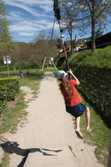 Jeune fille s'élançant sur une tyrolienne dans une aire de jeux