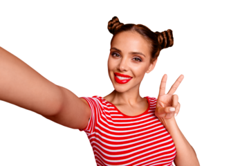 Young woman with funky mood making v-sign and selfie on the front camera of smartphone, playful and happy isolated on red background