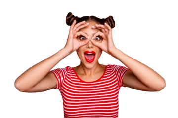 Pretty girl with surprised face holding fingers near eyes like glasses: mask like super hero or owl isolated on red background