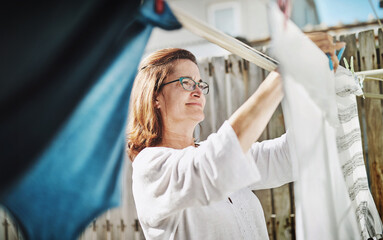 Mature woman, clothesline and laundry outdoor with household domestic chores, spring cleaning and housekeeping. Hanging clothes, fabric or white cotton sheet, cleaner and housework in Australia