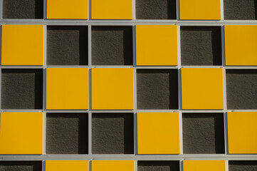Close-up picture of the texture of the building wall. Yellow and black colours on the building wall.