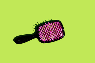 Black plastic hairbrush on vibrant green background, perfect for hair care routine, professional...