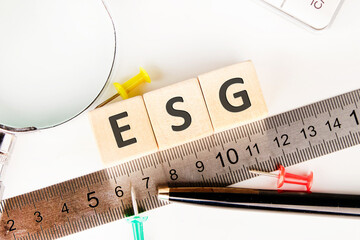 ESG concept of environmental, social and governance. words ESG on wooden cubes near a measuring ruler, magnifying glass, calculator.