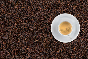 Top view background of aromatic brown coffee beans and cup of espresso.
