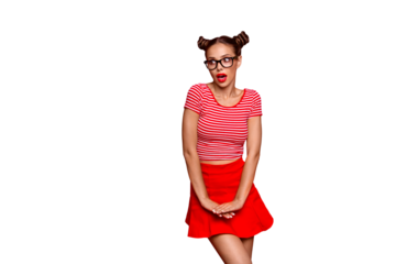 Charming brunette girl with a surprised face coquettishly and shyly holding her hands on a skirt lifting her knee isolated on vivid red background