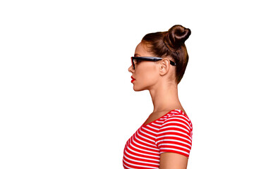 Half-faced side profile view portrait of serious and confident young woman in striped shirt and spectacles isolated on red vivid background with copy space