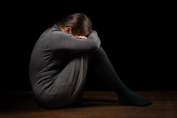 Domestic violence. Sad child sitting on floor in dark room