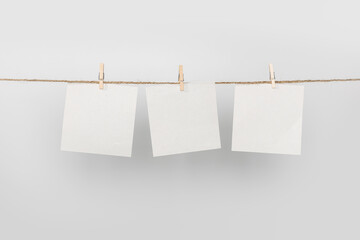 3 Note paper cards hanging with wooden clip or clothespin on rope string peg isolated on white...