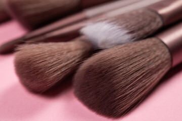 Various makeup brushes over pink background