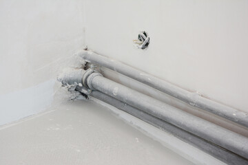 Close up on pvc pipes in the kitchen wall  corner under construction after plastering.