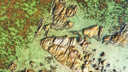 Aerial drone view of rocks on the shallow and clean water of an island