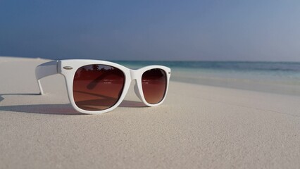White sunglasses on a tropical beach in Maldives