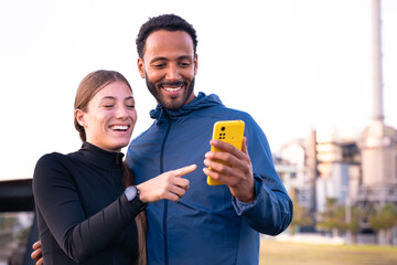 Young couple using a social media app on smartphone while exercising outdoors.