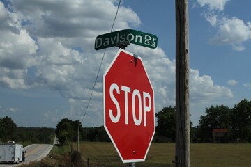 Closeup of a stop sign on a road with field under the cloudy sky