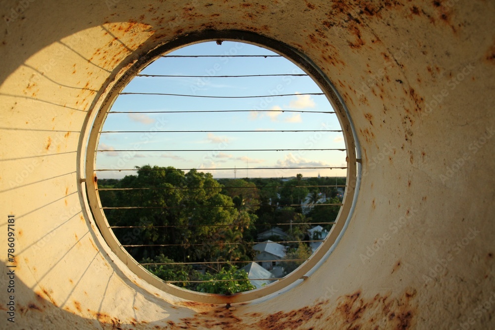 Wall mural Round rusty fenced window to the green park