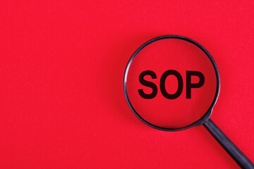Magnifying glass with acronym SOP or Standard Operating Procedure isolated on red background - obrazy, fototapety, plakaty