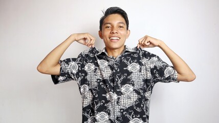 Handsome young Asian man posing proudly wearing batik clothes made in native Indonesian culture