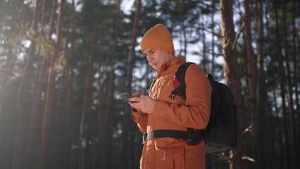 travel navigation. man tourist looking for a way in a smartphone navigation in winter in a forest park. male hacker navigates in close-up the forest navigation looking for a way in winter in park