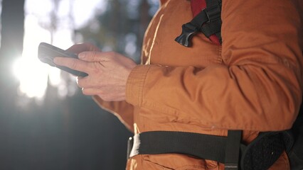 travel navigation. man tourist looking for a way in a smartphone navigation in winter in a forest park. male hacker navigates in the forest navigation looking close-up for a way in winter in park