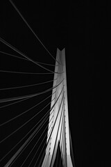 Low angle of a pole with cables of Erasmusbrug bridge in Rotterdam, Netherlands under night sky