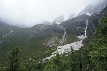 Obraz premium Scenic shot of amazing mountains covered in fog in Daocheng Yading national park, Sichuan, China