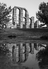 Vertical grayscale shot of the historic Acueducto de los Milagros Roman aqueduct in Merida, Spain - obrazy, fototapety, plakaty