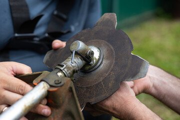 Close-up of fixing a metal disk for cutting grass on a trimmer. Changing the attachment on a...