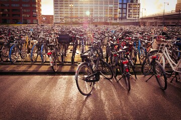 Closeup shot of bunch of bicycles parked in a main station of Amsterdam, Netherlands - obrazy, fototapety, plakaty
