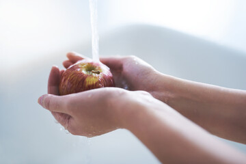 Water, hands and person washing apple, hygiene in kitchen with sustainability and disinfection,...