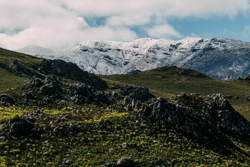 Beautiful shot of a green hill against a snowy mountain range in Cape Town, South Africa