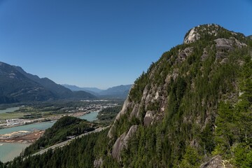 Beautiful view of sea and mountains under blue sky from behind a cliff covered with green