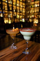 Vertical shot of two fruity alcoholic beverages on a wooden table at a nightclub