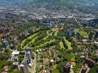 Aerial view of Medellin city with high buildings and green nature on a bright sunny day