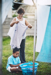 Backyard, grandmother and grandchild with laundry, help and chore with summer and bonding together....