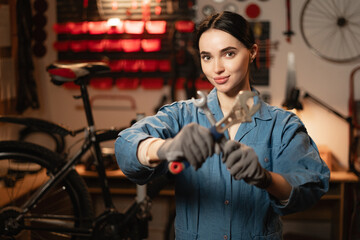 Bicycle care maintenance and servicing concept. Portrait of female technician mechanic using the wrench to repairing bike service support in garage or repair workshop.