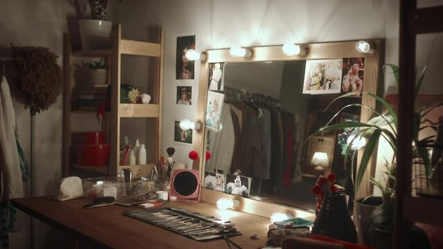 Interior of theatre dressing room with vanity desk, illuminated mirror and stage make-up props