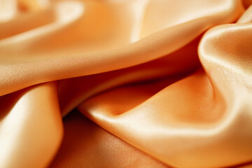 Close-up of yellow silk satin, draped fabric, gold color, elegant background. Beautiful wavy area for design, Close-up of blurred or blurred.