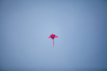 A red kite flying against a blue sky.