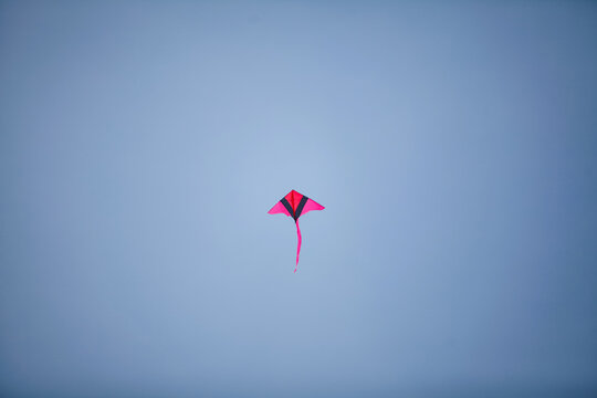 A red kite flying against a blue sky.