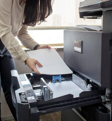 a staff worker at the company is tidying up the paper and then inserting it into the paper area...