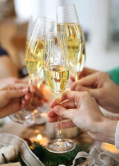 Group of friends toasting with champagne while having Christmas dinner
