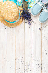 Straw hat, lavender flowers and  fabric moccasins on white planks vacation planning background flat lay with copy-space