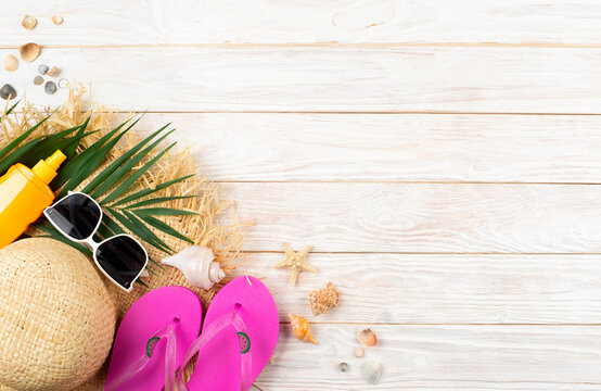 Vacation travel planning simple background of palm leaves, straw hat, flip flops on white planks flat lay with copy-space