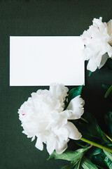 Mother's day banner with blank white card and bouquet of white peonies flowers on green background