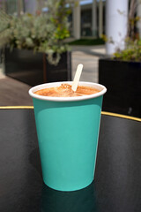 Cardboard takeaway cup of coffee on black table outdoors