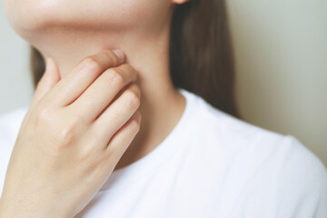 sore throat pain. Closeup of young woman sick holding her inflamed throat using hands to touch the...